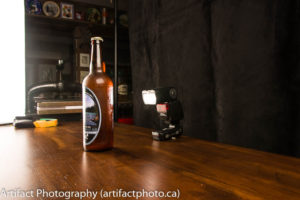 Speedlight flash positioned directly behind bottle